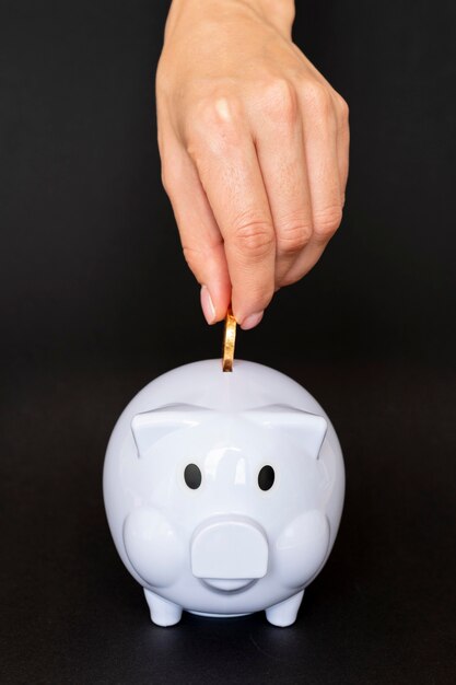 Front view person placing a coin in a piggy bank