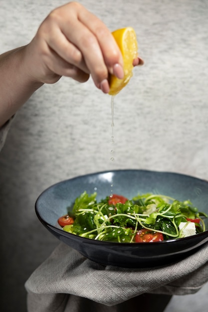 Foto gratuita vista frontale della persona che versa il succo di limone in una ciotola di insalata