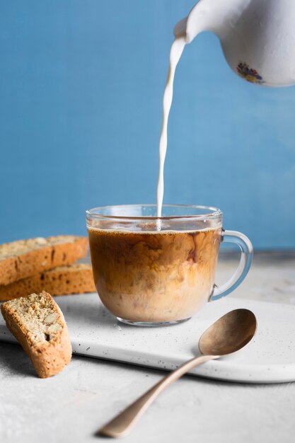 Front view person pouring milk in glass with coffee