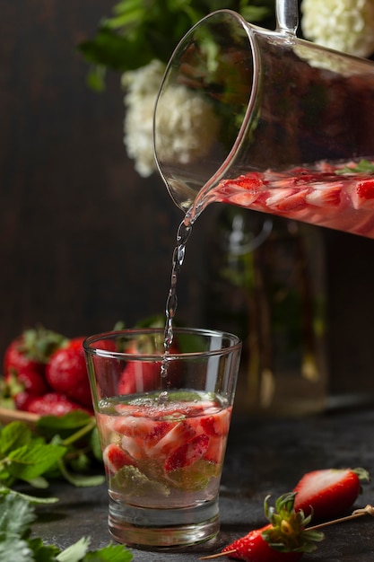 Front view person pouring strawberry infused water