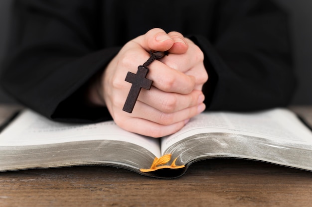 Vista frontale della persona che prega con croce e libro sacro