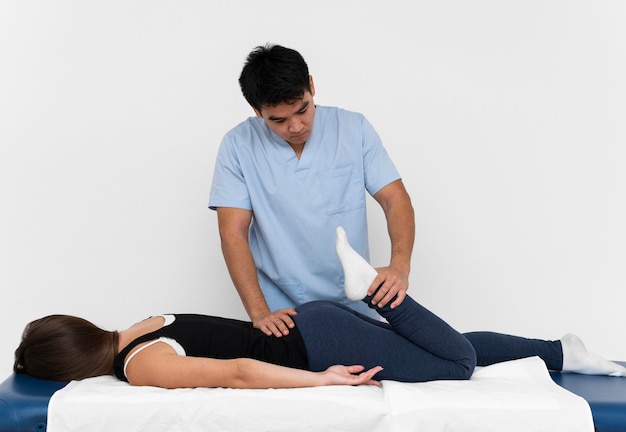 Front view of physiotherapist doing leg exercises with woman