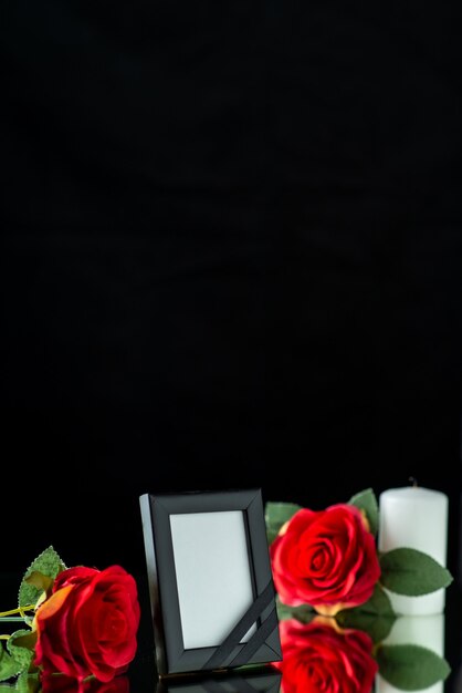 Front view of picture frame with candle and red rose on black