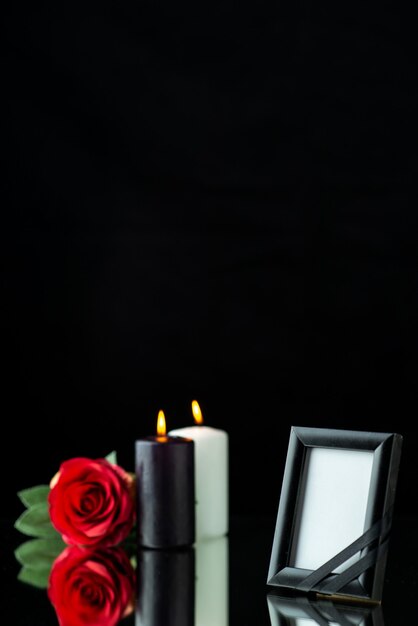 Front view of picture frame with candles and red rose on black