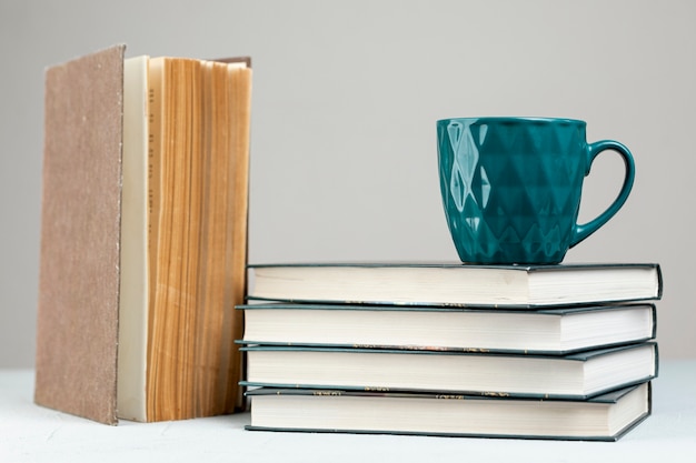 Free photo front view pile of books with a mug