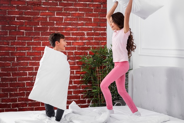 Free photo front view pillow fights between siblings