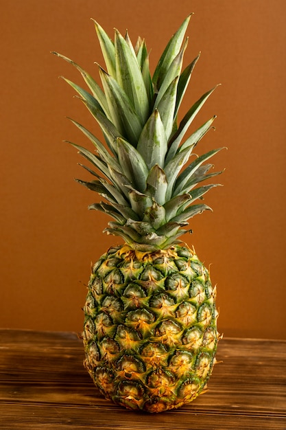 A front view pineapple juicy mellow exotic isolated on the brown wooden desk tropical fruit juicy