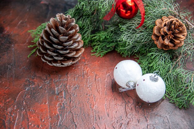 Front view pinecones pine tree branches xmas ball toys on dark red background free space xmas photo