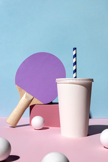 Front view of ping pong balls and paddle and paper cup