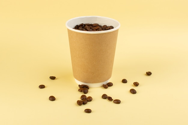 黄色の壁に茶色のコーヒーの種を正面から見たプラスチック製のコーヒーカップ