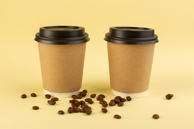 正面のプラスチック製のコーヒーカップの配達コーヒーペアと黄色の表面に茶色のコーヒーの種