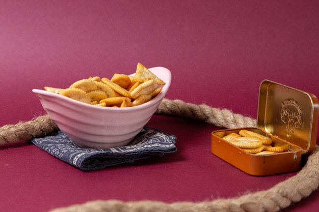 Front view plate with crackers pink plate with ropes on purple