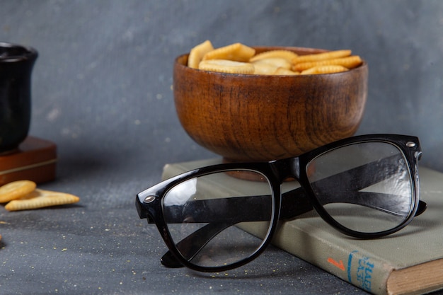 Foto gratuita piastra di vista frontale con cracker con occhiali da sole su grigio
