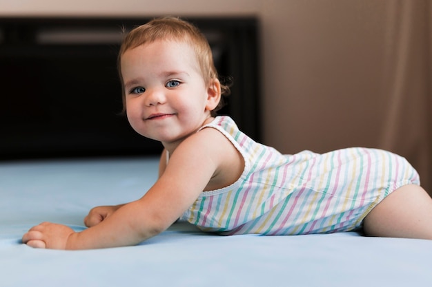 Front view of playful baby in bed