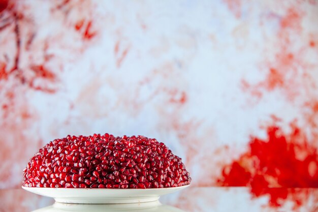 Front view pomegranate salad in cake shape inside plate on a light-red