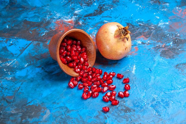 Front view pomegranate seeds in little wooden bowl a pomegranate on blue background free place