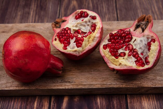 Front view pomegranates on a cutting board on a wooden wall