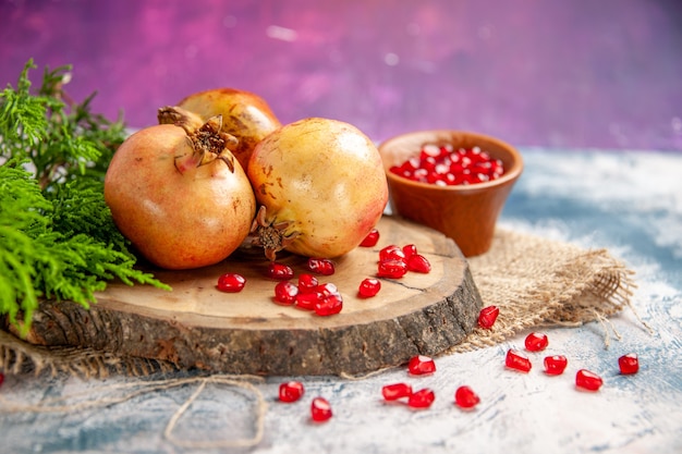 Front view pomegranates on round cutting board scattered pomegranate seeds in bowl on pink free place