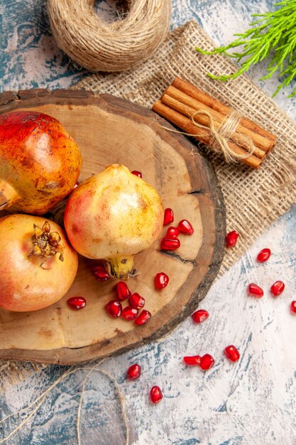 Front view pomegranates on round cutting board scattered pomegranate seeds cinnamon on blue-white background