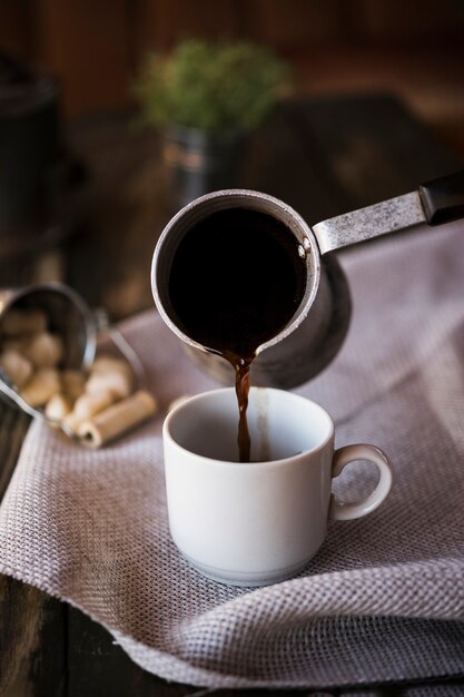 Вид спереди наливая кофе из чайника в чашку