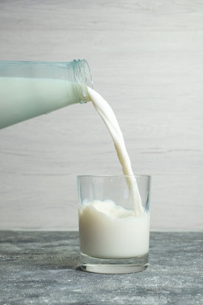 白の小さなガラスに牛乳を注ぐ正面図、飲み物の乳製品乳製品