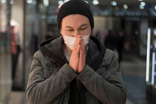 Foto gratuita vista frontale dell'uomo orante che indossa maschera medica