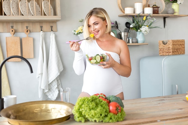 Free photo front view pregnant woman eating a salad