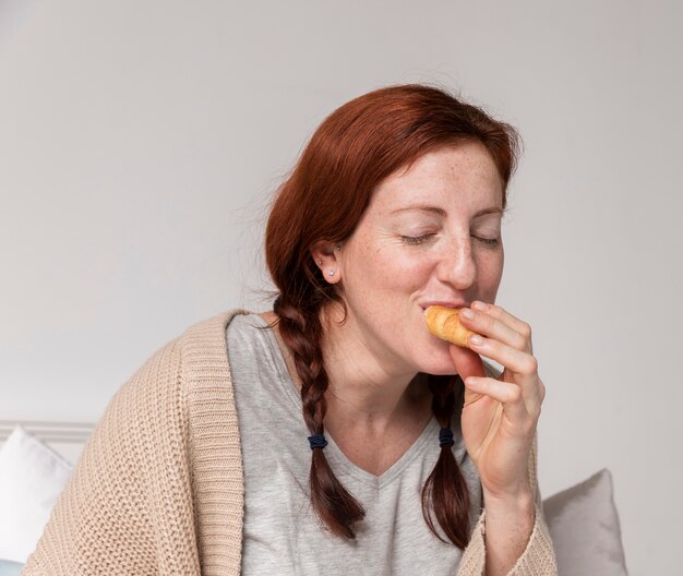 Front view pregnant woman enjoying croissant