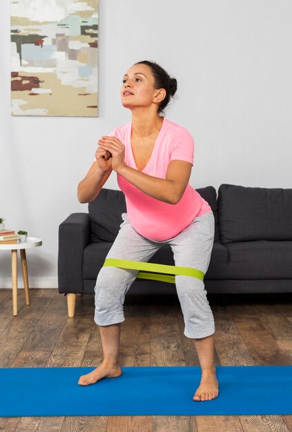Front view of pregnant woman at home exercising with elastic band