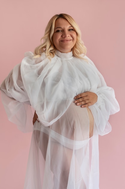 Free photo front view pregnant woman posing in studio