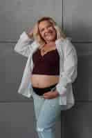 Free photo front view pregnant woman posing in studio