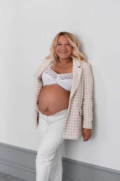 Free photo front view pregnant woman posing in studio