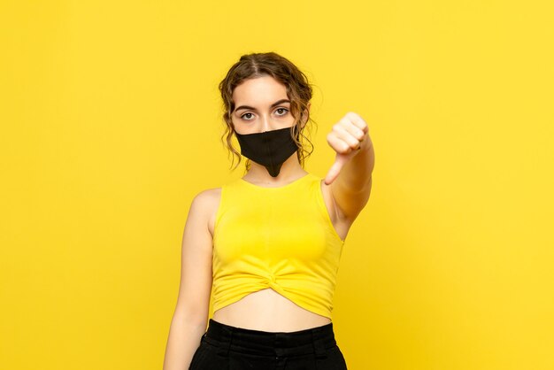 Front view of pretty female in black mask on yellow