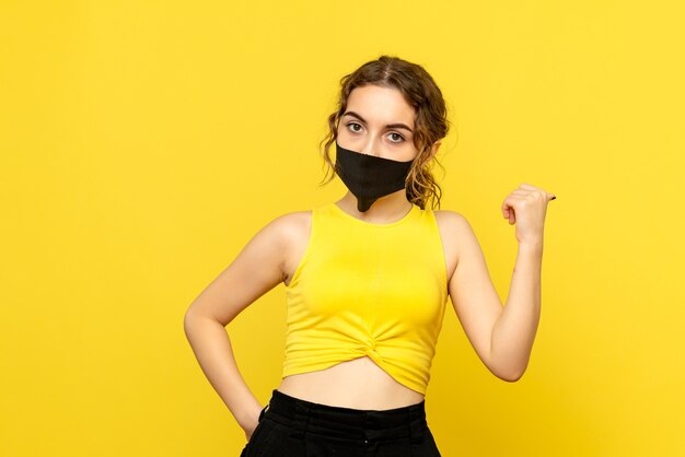 Front view of pretty female in black mask on yellow