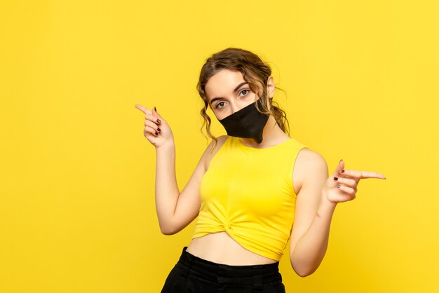 Front view of pretty female in black mask on yellow