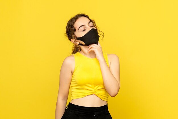 Front view of pretty female in black mask on yellow