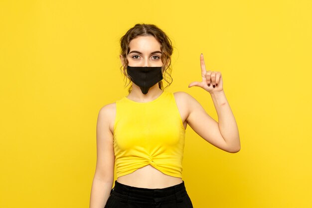 Front view of pretty female in black mask on yellow