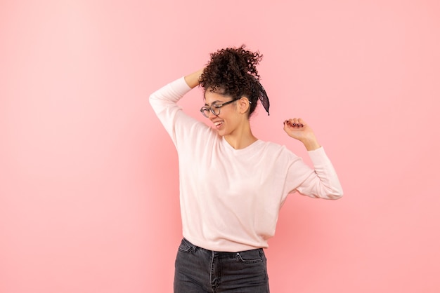 Vista frontale della femmina graziosa che gioisce felicemente sul rosa