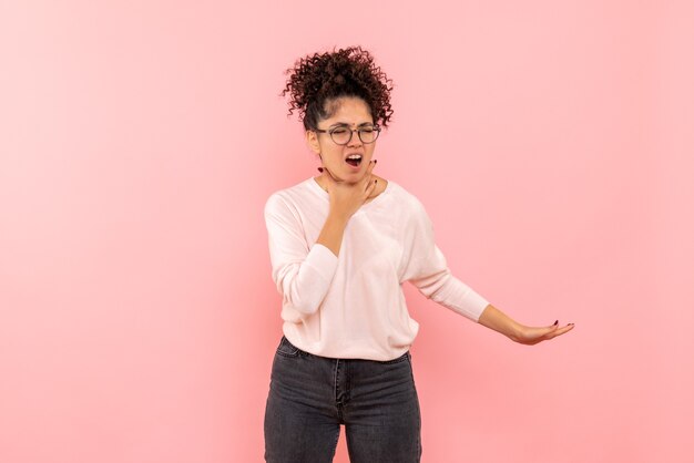 Front view of pretty female having sore throat on pink