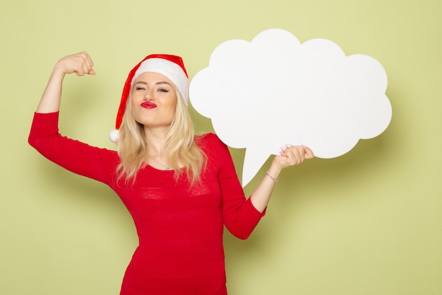 Front view pretty female holding big white sign on green wall christmas snow photo holidays emotion new year