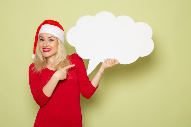 Front view pretty female holding big white sign on a green wall new year snow holidays photo christmas emotion