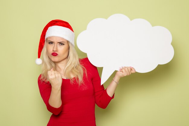 Front view pretty female holding cloud shaped white sign on green wall christmas photo holiday emotion new year
