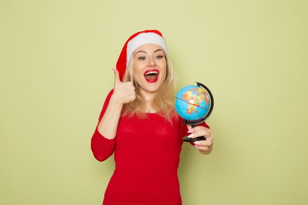 Front view pretty female holding little earth globe on green wall holiday emotion christmas new year snow colors