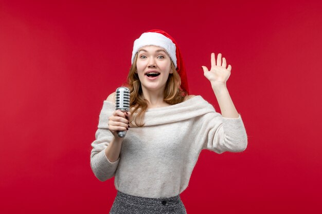 Front view of pretty female holding mic on red