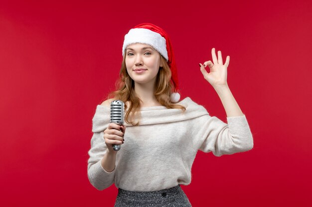 Front view of pretty female holding mic on red