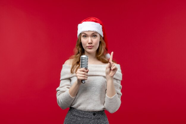 Вид спереди красивой женщины, держащей микрофон на красном