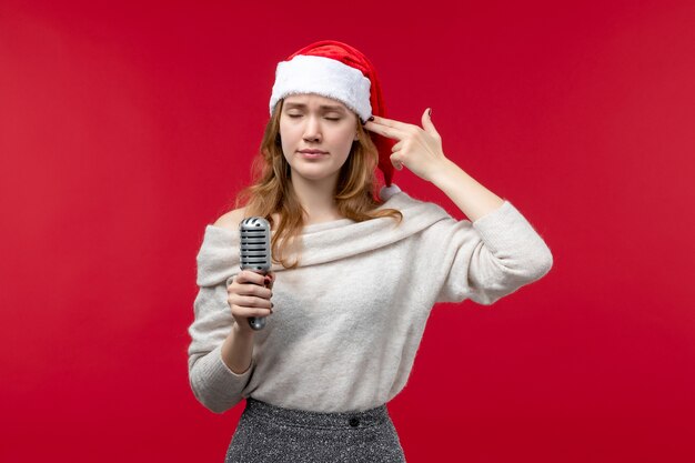 Front view of pretty female holding mic on red