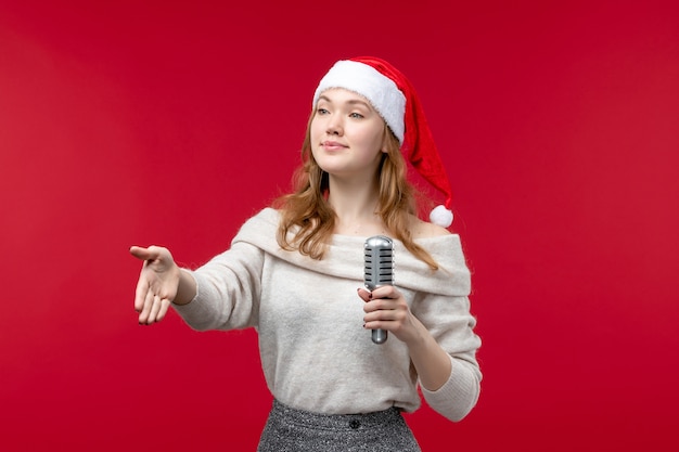 Front view of pretty female holding mic on red