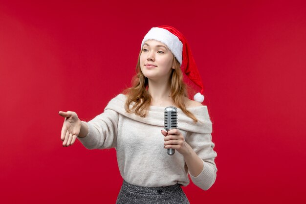 Front view of pretty female holding mic on red