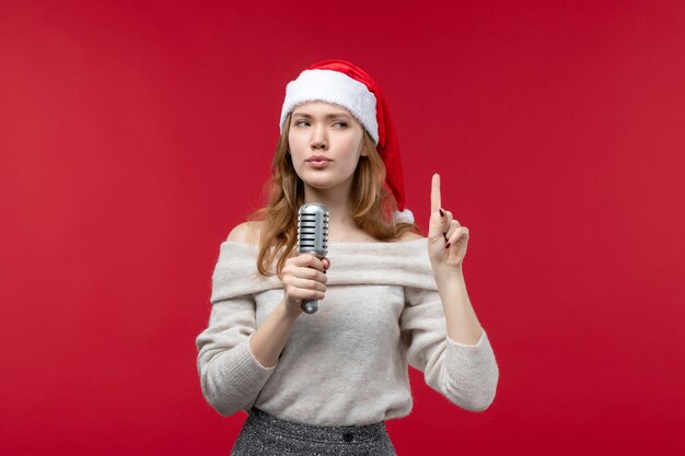 Front view of pretty female holding mic on red